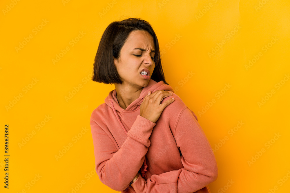 Young hispanic woman isolated on yellow having a shoulder pain. Young hispanic woman isolated on yellow having a shoulder pain.