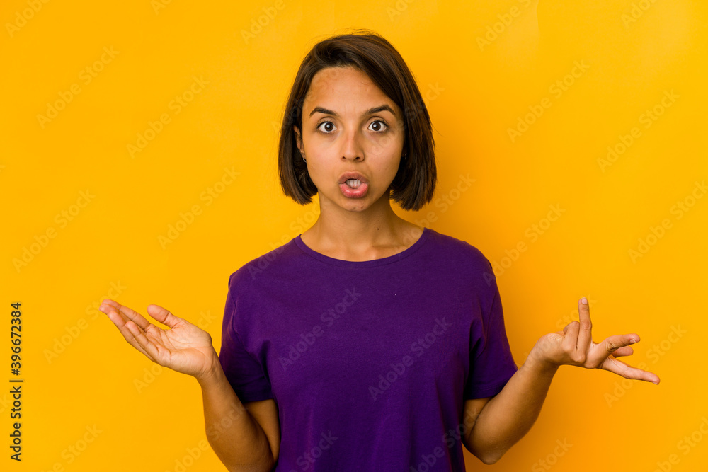 Young hispanic woman isolated on yellow surprised and shocked. Young hispanic woman isolated on yellow surprised and shocked.