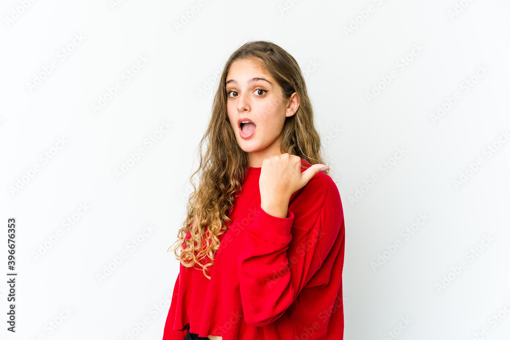 Young caucasian woman points with thumb finger away, laughing and carefree.