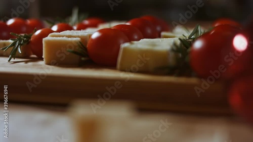 Flat lay of cheese and tomatoes. Slices of cheese, tomatoes and rozmarin arranged in a shape of Christmas Tree. Food for Christmas holiday. Slowmotion, side view photo