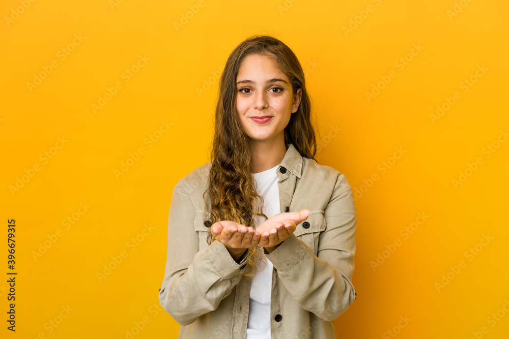 Young caucasian woman holding something with palms, offering to camera.