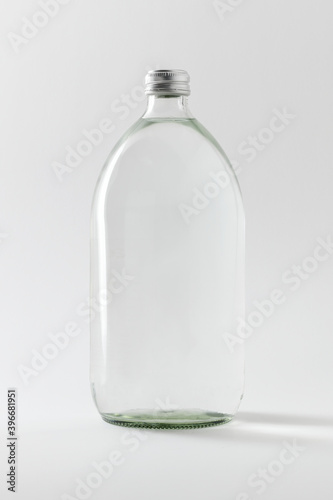 Empty clear glass bottle on off white background photo