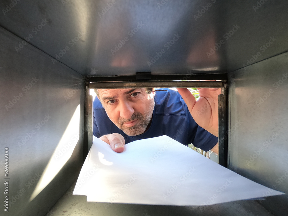 Adult man (age 40-50) sending or collecting mail from a postal box.