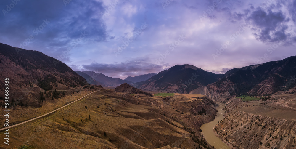 Aerial Panoramic View of a Scenic Highway in the Valley surrounded by Canadian Dramatic Sunset Sky. Mountain Landscape. Taken near Lillooet, British Columbia, Canada.
