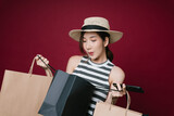 Excited beautiful woman wear hat holding shopping paper bags isolate over red background.