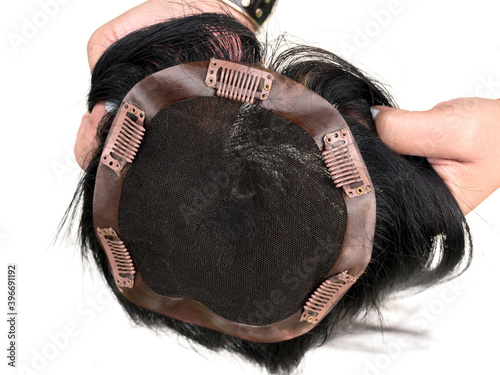Holding a hair toupee or topper exposing the inside and showing the clips to help secure the hairpiece. photo