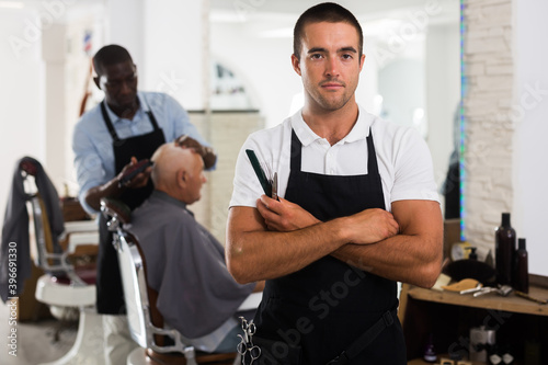 Portrait of confident man hairdresser posing in modern barber shop
