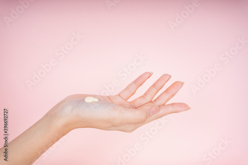 Closeup of beautiful woman's hands with cream lotion isolate on pink background.