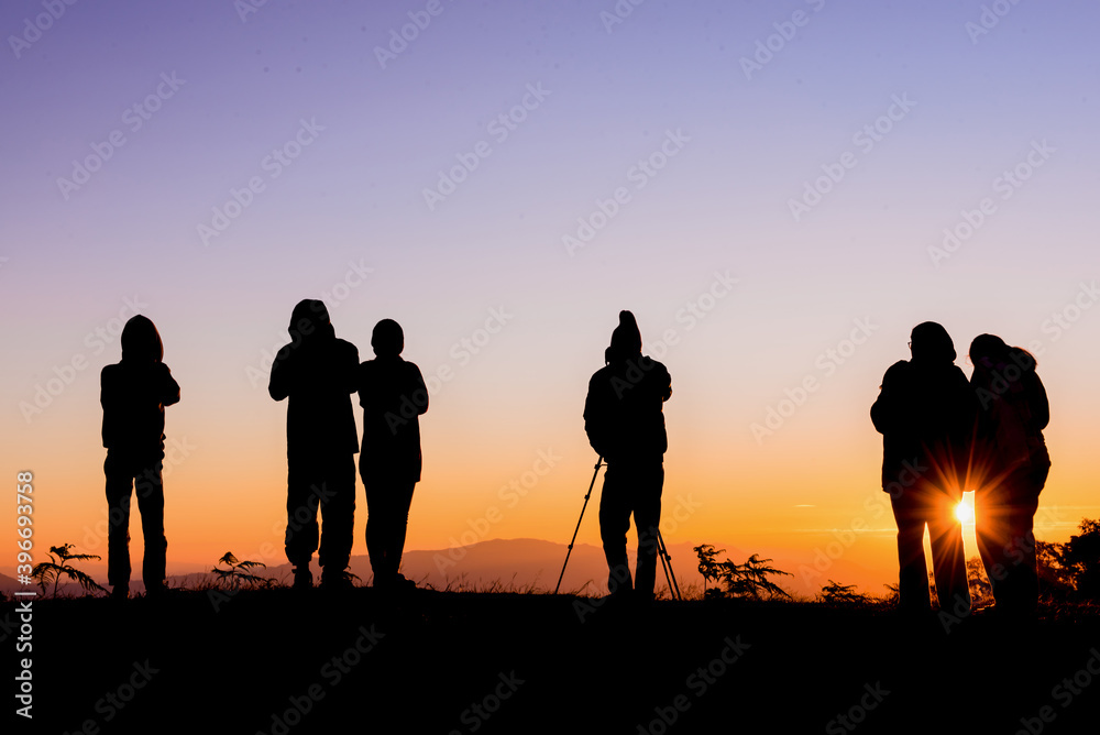 A silhouette of a tourist standing on a mountain sunrise photographing in Mae Hong Son, Thailand.