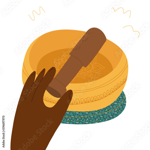 A hand holding wooden kansa wand and do healing therapy with singing bowl and cushion. 