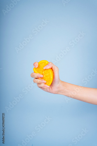 Hand of woman squeeze slice of orange.