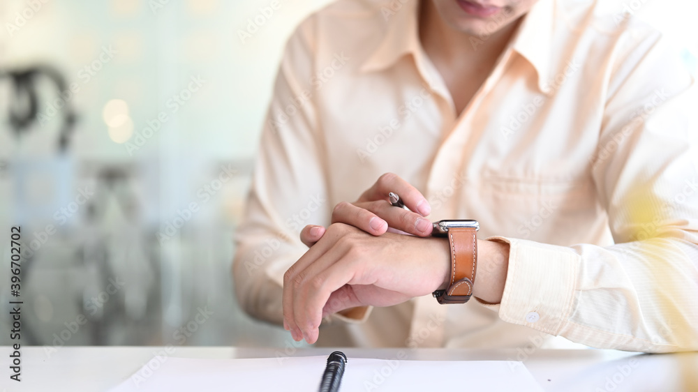 Cropped shot of businessman is looking at a smartwatch on his hand.