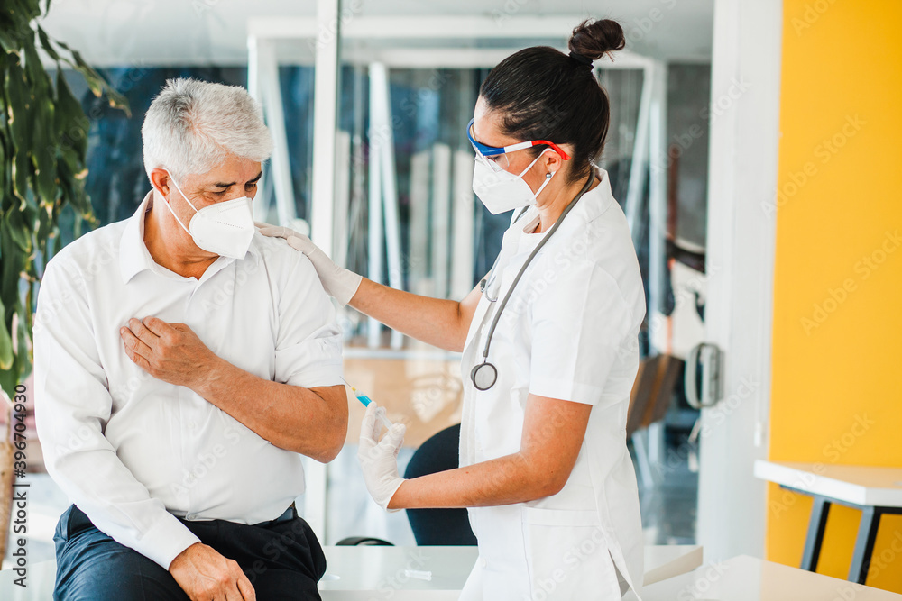 old latin man receiving vaccine shot for a mexican doctor woman with facemask for coronavirus pandemic in Mexico city old latin man receiving vaccine shot for a mexican doctor woman with facemask for coronavirus pandemic in Mexico city