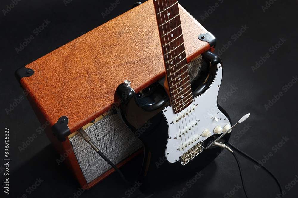 Naklejka premium Guitar combo with black guitar on black background.