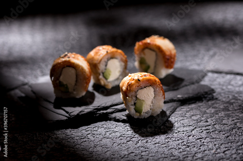 Appetizing rolls on a textured black background. Japanese food concept. Close-up. Copy space.