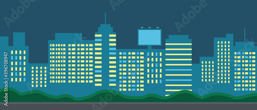 Night city landscape. Skyscrapers, buildings, offices, huge flat billboard. Glowing windows of houses. Electricity, urban illumination. Green bushes. Summer or autumn evening. Urban night landscape