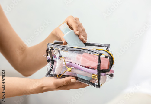 Female hands and cosmetics bag on light background