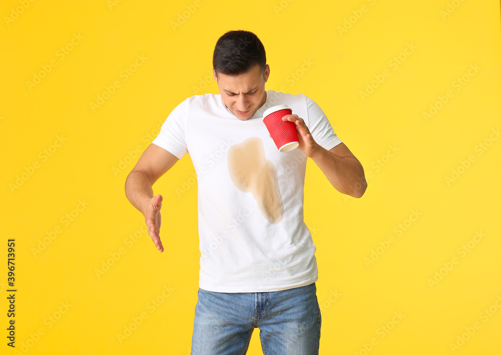 Stressed young man with coffee stains on his t-shirt on color background - obrazy, fototapety, plakaty 