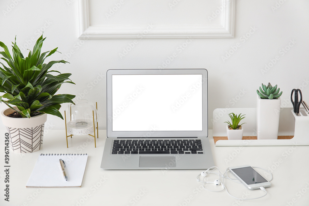 Stylish workplace with laptop near white wall
