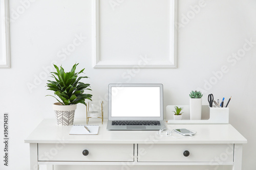 Stylish workplace with laptop near white wall © Pixel-Shot