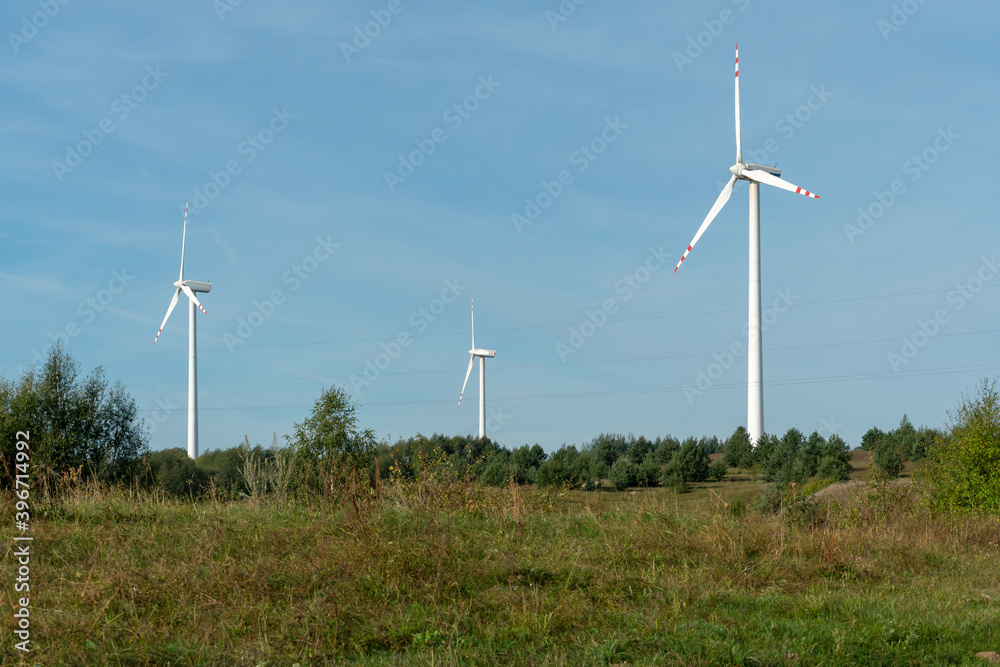view of the windmill against the blue sky. Wind turbines in the field or along roads. Renewable energy source. Use of natural resources for the benefit of humanity. view of the windmill against the blue sky. Wind turbines in the field or along roads. Renewable energy source. Use of natural resources for the benefit of humanity.