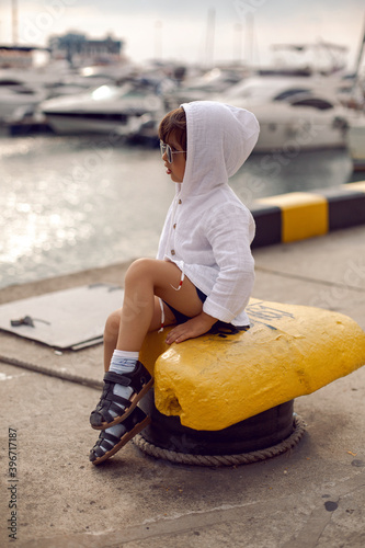 boy child traveler sitting on the Marina with yachts in Sochi in the summer photo