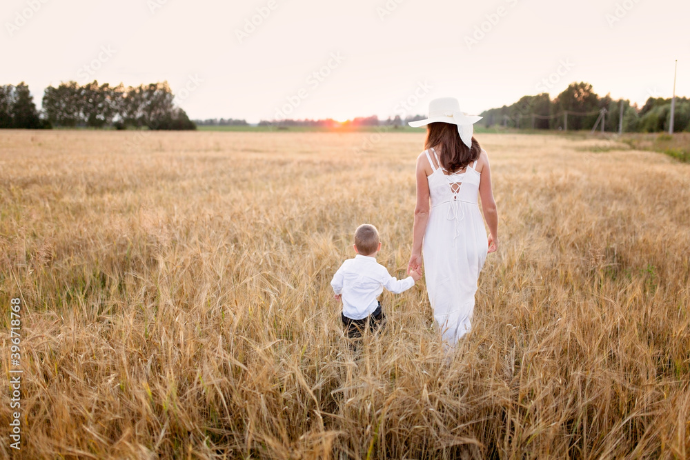 Caucasian beautiful mother hugs her child son in the summer wheat field at sunset, summer and harvest, natural products and relaxation in the countryside, motherhood Caucasian beautiful mother hugs her child son in the summer wheat field at sunset, summer and harvest, natural products and relaxation in the countryside, motherhood