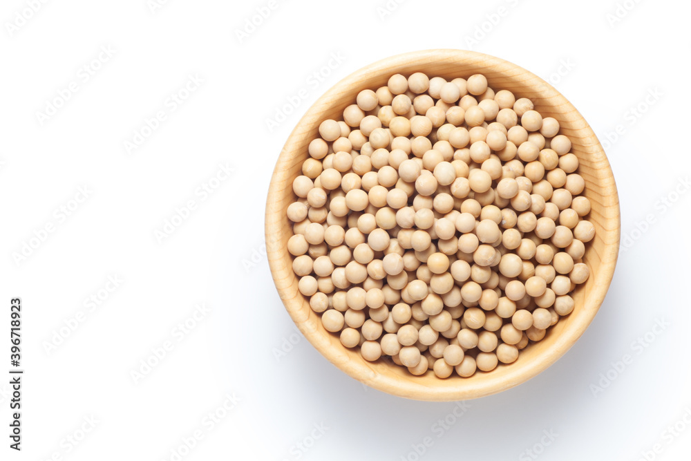 Soybean seeds in a wooden bowl isolated on white background. Top view.