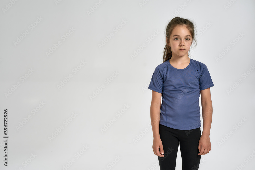 Little sportive girl child in sportswear looking at camera, while standing isolated over white background Little sportive girl child in sportswear looking at camera, while standing isolated over white background