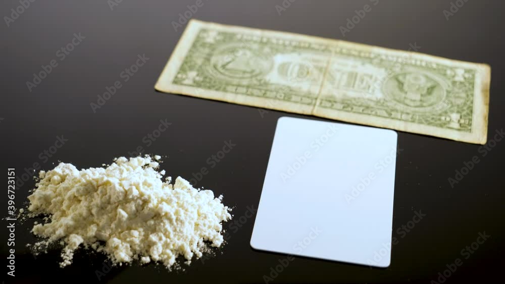 Lines of cocaine and a dollar bill. Cocaine lines shots on a black table glass. Cocaine powder, Credit card, close up, toned. Drug abuse concept. White poder on black table