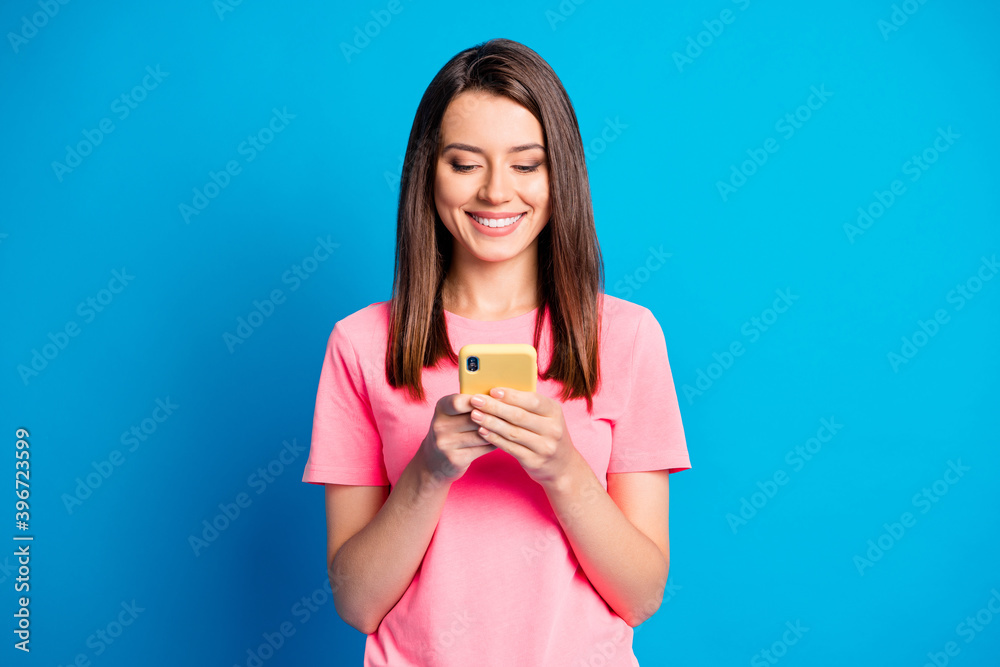 Photo portrait of female student smiling using app on smartphone isolated on vivid blue color background Photo portrait of female student smiling using app on smartphone isolated on vivid blue color background