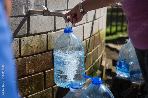 Collecting natural spring water with day zero water crisis with plastic water bottle at Newlands natural spring Cape Town South Africa with water shortage disaster.