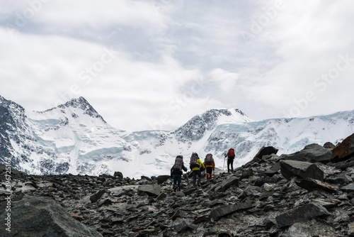 a group of climbers goes through the rocky mountains on the background of the top of " Belukha"