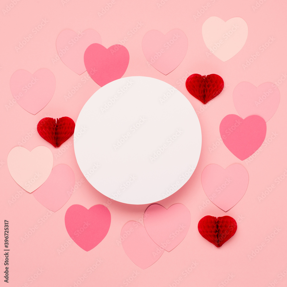 Pink, red paper hearts and empty frame on pastel pink background. Valentines day concept.