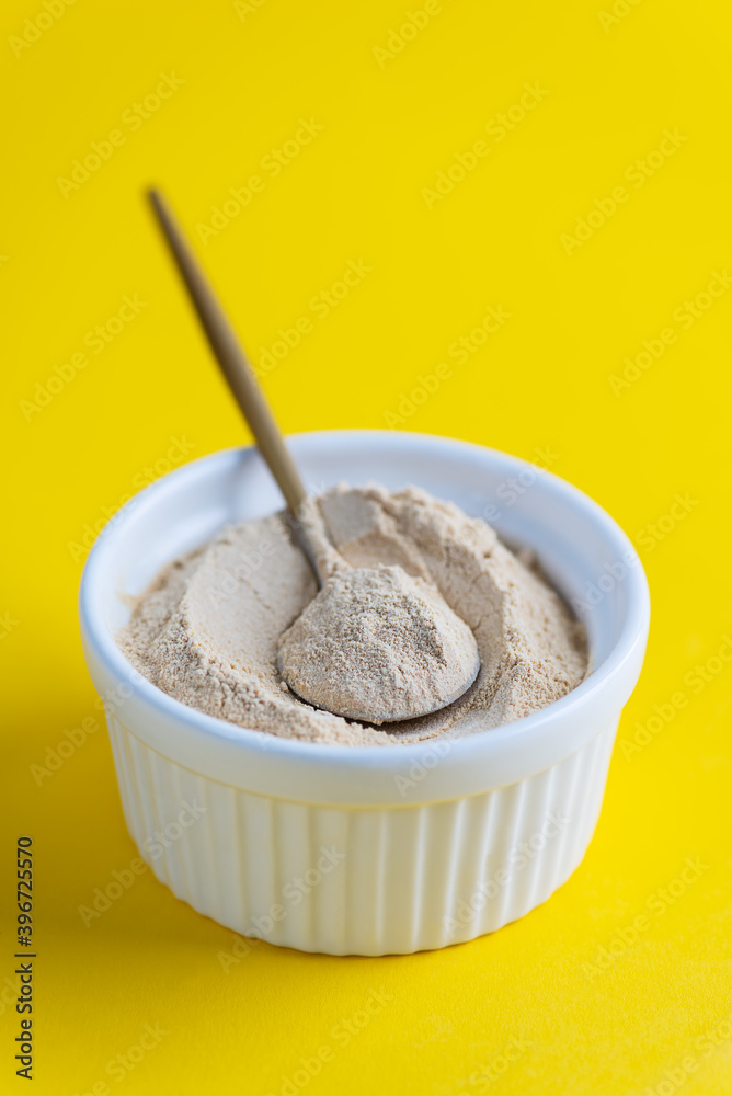 Sunflower lecithin in a bowl with a spoon on a yellow background. Sunflower lecithin in a bowl with a spoon on a yellow background.