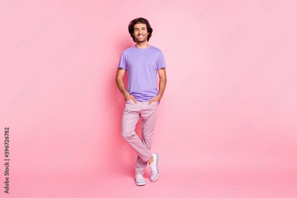 Full length photo of flirty guy palms pockets wear purple shirt trousers sneakers isolated pastel pink color background Full length photo of flirty guy palms pockets wear purple shirt trousers sneakers isolated pastel pink color background