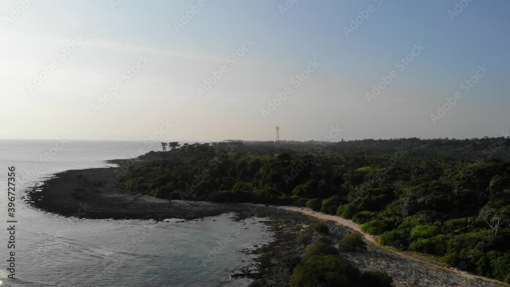 Forward and downward drone motion view of andaman island at sunset with the andaman sea in the background and farmland in the foreground small homesteads , forest and fields radio tv internet tower