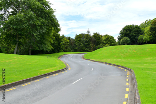 View of asphalt road winding through green hills