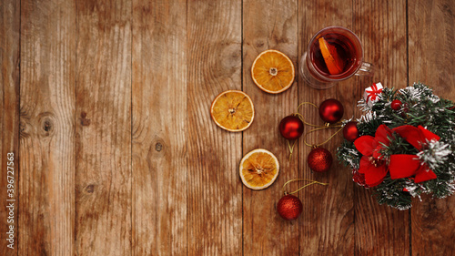 Christmas mulled wine in glass cup on a wooden table with dry oranges