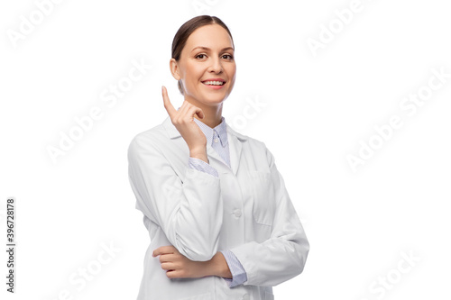 medicine, profession and healthcare concept - happy smiling female doctor in white coat pointing finger up photo