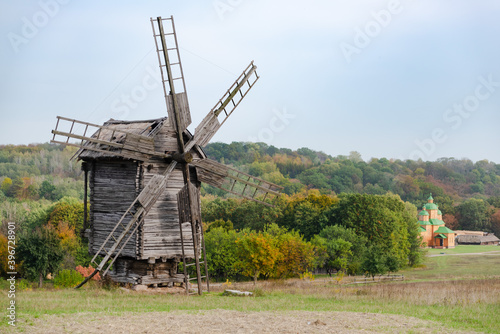 Beautiful autumn view of old wooden windmill in countryside. Ukrainian village.