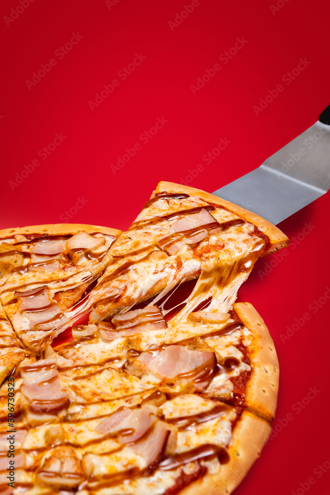 Lifting slice of a pizza with very much cheese melting. Texas style pizza on a red background