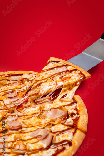 Obraz na płótnie Lifting slice of a pizza with very much cheese melting. Texas style pizza on a red background w salonie
