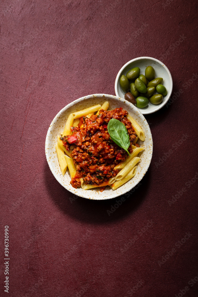 Overhead view of bolognese pasta on red background Overhead view of bolognese pasta on red background