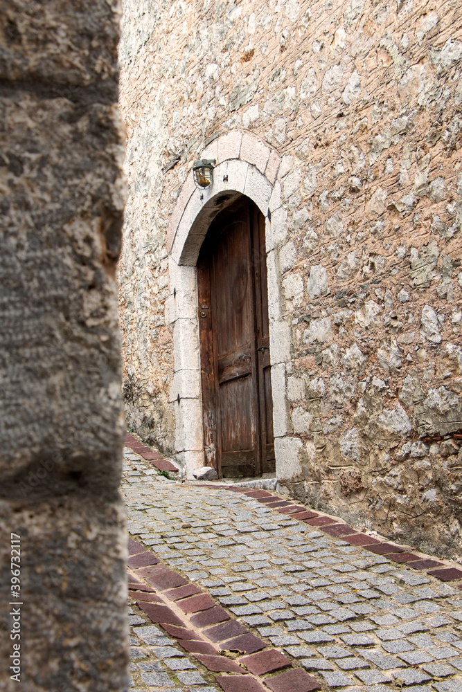 Old wooden door on wall made of stone.