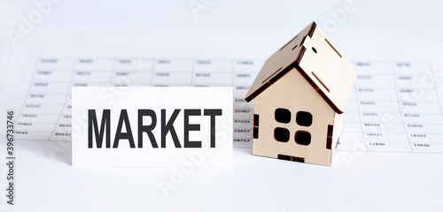 Closeup of house wooden model with blank for text MARKET on chart background.