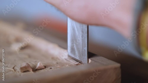 macro. a woodcarver makes a wooden tray. The craftsman processes the walnut board with a flat impact chisel