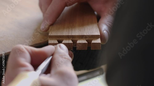 a joiner carves a dovetail joint into an oak plank with a wood chisel. carpentry, craftsmanship, handicrafts. the sounds of carpentry tools