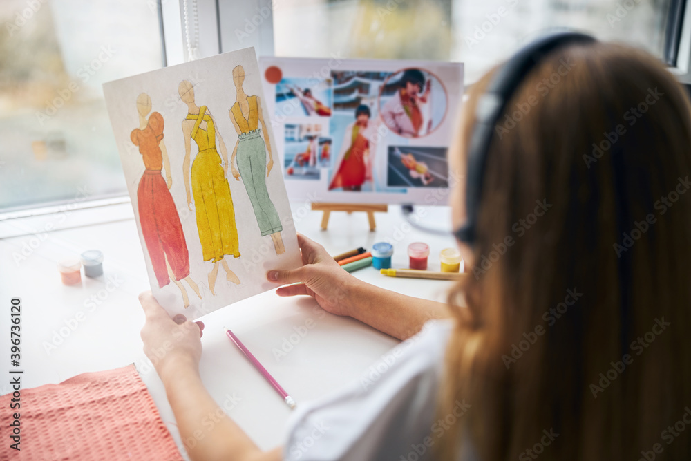Girl in a headset holding sketches in her hands Girl in a headset holding sketches in her hands
