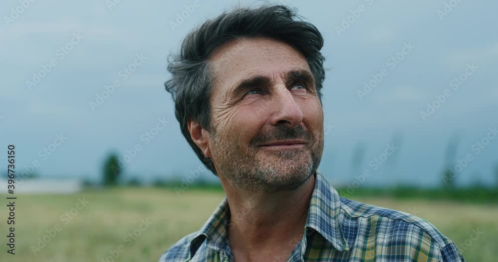 Cinematic shot of a mature male farmer satisfied with his work is enjoying a nature around him on a countryside farm fields. Cinematic shot of a mature male farmer satisfied with his work is enjoying a nature around him on a countryside farm fields.